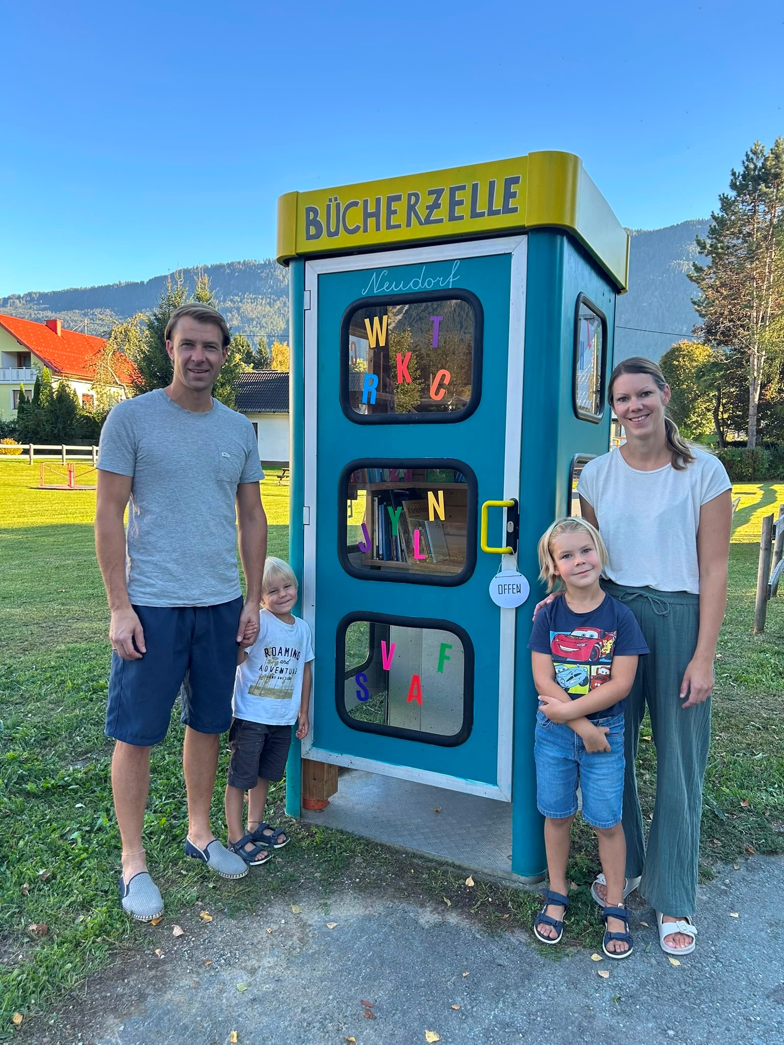 Familie vor Büchertauschzelle in Neudorf